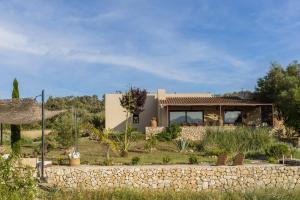 une maison au milieu d'un champ avec un mur en pierre dans l'établissement Vista Verde, à Sineu