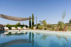 a swimming pool with chairs and a hammock next to it at Vista Verde in Sineu