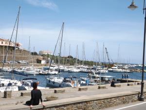 a woman sitting on a wall looking at boats in the water at B&B Il Gatto Pescatore in Stintino