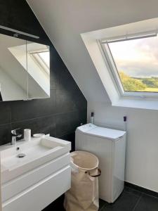 a bathroom with a toilet and a sink and a skylight at Chez mamy Odette- Appartement lumineux en bord de mer in Plonévez-Porzay