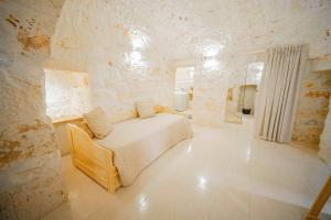 a bedroom with a bed and a stone wall at Il Fiore della Vita Trulli Country house in Conversano