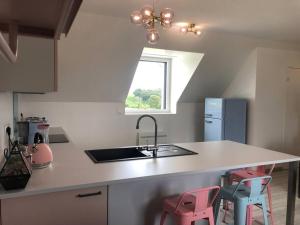 a kitchen with a sink and two pink stools at Chez mamy Odette- Appartement lumineux en bord de mer in Plonévez-Porzay +5 photos