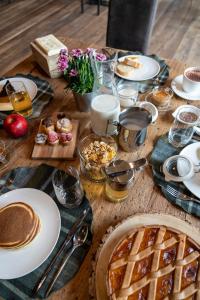 una mesa de madera cubierta con platos de comida y repostería en Agriturismo Rini en Bormio