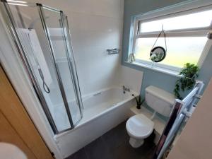 La salle de bains est pourvue d'une baignoire, de toilettes et d'une douche. dans l'établissement Perfect Cowes retreat with Hot Tub, à Cowes