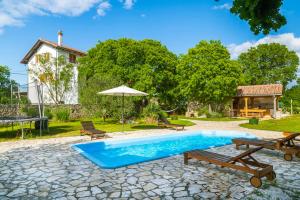 a pool with benches and an umbrella and a house at Villa Daja - Adriatic Luxury Villas in Oklaj