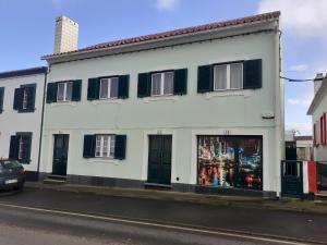 un edificio blanco con persianas verdes en una calle en Friends Place, en Praia da Vitória