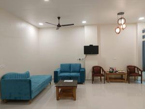 a living room with two blue chairs and a tv at HOTEL KAVANA in Varanasi