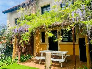 uma mesa de piquenique em frente a uma casa com flores roxas em Apartamentos Santillana del Mar em Santillana del Mar