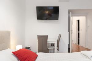 a bedroom with a bed and a desk with a television on the wall at Modern 1BR Apart- Suitable for Longstays in Vienna