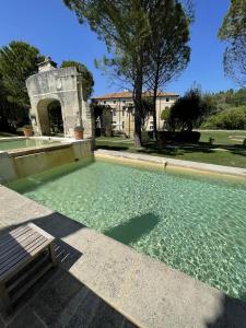 einem Wasserpool mit einer Bank vor einem Gebäude in der Unterkunft Chateau Talaud in Loriol-du-Comtat