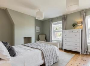 a bedroom with a bed and a dresser and a window at Fallow Cottage in Lyndhurst