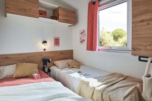 a bedroom with two beds and a window at Camping Ty Nénez in Pont-Scorff