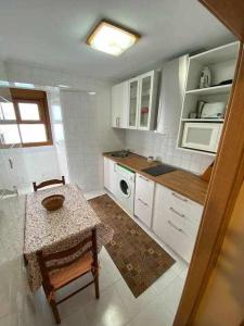 a small kitchen with a table and a microwave at Durmiendo con el mar in Lastres