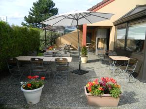 d'une terrasse avec des tables, des chaises et un parasol. dans l'établissement Campanile Epernay - Dizy 51530, à Épernay