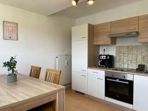 a kitchen with white cabinets and a wooden table at Maxi'Seeblick Apartments in Seeboden