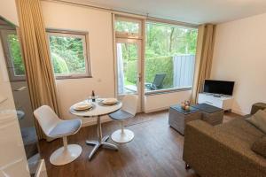 - un salon avec une table, des chaises et un canapé dans l'établissement Heerlijk vakantiehuisje op rustig Natuurpark, à Otterlo