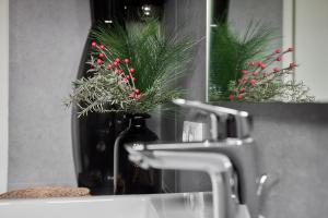 lavabo en el baño con jarrón con flores rojas en el espejo en Schima Drosa Apartments - Studios - by Pferd auf Wolke, en Gaschurn