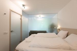 - une chambre avec un lit blanc et un miroir dans l'établissement Heerlijk vakantiehuisje op rustig Natuurpark, à Otterlo