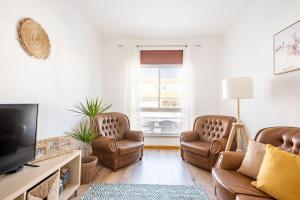 a living room with two chairs and a flat screen tv at Casa Alto da Serra Sesimbra in Sesimbra