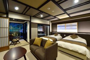 a bedroom with two beds and a chair and a couch at Ryokan Sumiya Kihoan in Kameoka