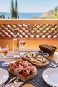 Les Terrasses du Bailli في لو رايول-كاناديل-سور-مير: طاولة مع اثنين من البيتزا وكأسين من النبيذ