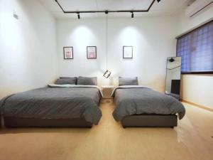 Duas camas num quarto grande com paredes brancas em S&G Homestay - JB@Permas Jaya em Johor Bahru