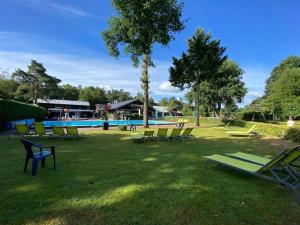 a group of lawn chairs and a swimming pool at Knus huisje op kindvriendelijk park met zwembad in Otterlo