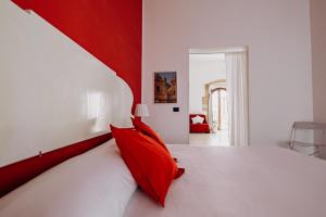 a red and white bedroom with a white bed with red pillows at Kyanos Residence in Siracusa