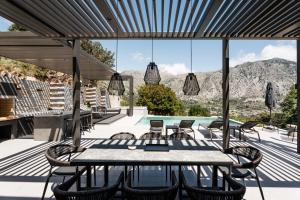 a patio with a table and chairs and a pool at Eumelia Iconic Villa, with Heated Pool & Whirlpool, By ThinkVilla in Asigonía