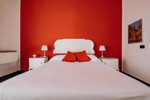 a bedroom with a white bed with red walls at Kyanos Residence in Siracusa