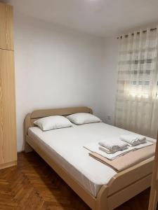 1 cama con sábanas blancas y almohadas en una habitación en Aleksija i Atanasija, en Bečići