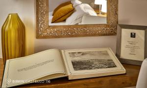 an open book sitting on a table next to a vase at Albergo Diffuso Birkin Castello in Cagliari