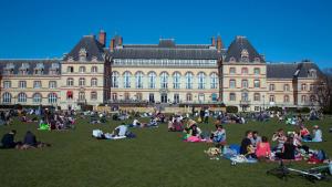 a group of people sitting on the grass in front of a building at Le 10 Cosy in Montrouge