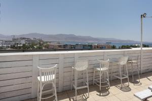 een rij stoelen en een tafel op een dak bij Little Prince Hostel-5 Min Walk To The Beach in Eilat