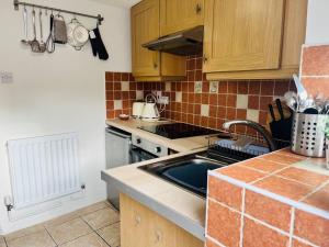 eine Küche mit Spüle und Herd in der Unterkunft Charming Brecon Beacons Cottage with Parking in Gilwern