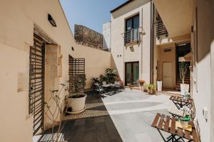 an internal courtyard of a house with benches and tables at Kyanos Residence in Siracusa