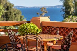 y balcón con mesa y sillas de madera. en Les Terrasses du Bailli en Rayol-Canadel-sur-Mer