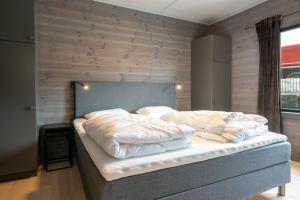 a bedroom with a bed with a wooden wall at Riddertunet apartment 104 - in the center of Beitostølen in Beitostøl