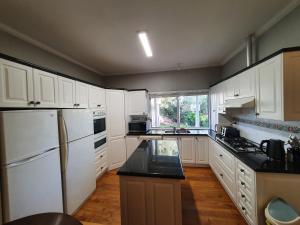 cocina con armarios blancos y encimera negra en Outstanding property Close to Melb Airport en Melbourne