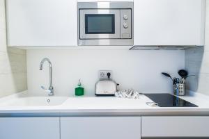 a white kitchen with a sink and a microwave at Hotel Vacanzy Urban Boutique Adults Only in Corralejo