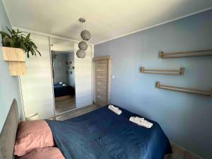 a bedroom with a blue bed and a mirror at Apartament Letnica in Gdańsk