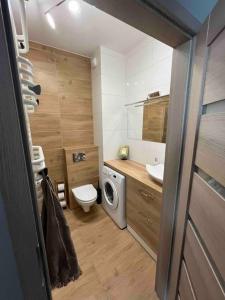 a bathroom with a toilet sink and a washing machine at Apartament Letnica in Gdańsk