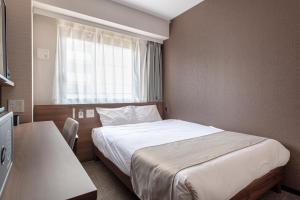 a hotel room with a bed and a window at Hotel Sanrriott Osaka Hommachi in Osaka