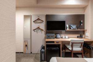 um quarto com uma secretária, um computador e uma televisão em Hotel Sanrriott Osaka Hommachi em Osaka