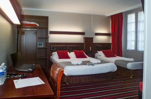 a hotel room with two beds and a desk with a laptop at Hotel De L'univers in Saint Malo +100 photos