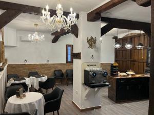 un restaurante con mesas y sillas blancas y una lámpara de araña en HABITACIONES LAS TERMAS en Guadix
