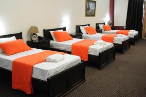 a room with four beds with orange and white sheets at Casablanca Hotel Ramallah in Ramallah