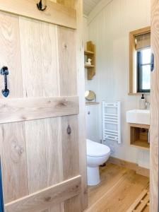 uma casa de banho com um WC e um lavatório em The Black Swan Shepherd Hut em Ketton