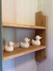 a wooden shelf with three white vases on it at The Black Swan Shepherd Hut in Ketton