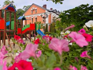 un parque infantil con sillas y flores coloridas frente a una casa en Hotel Koronny, en Zamość